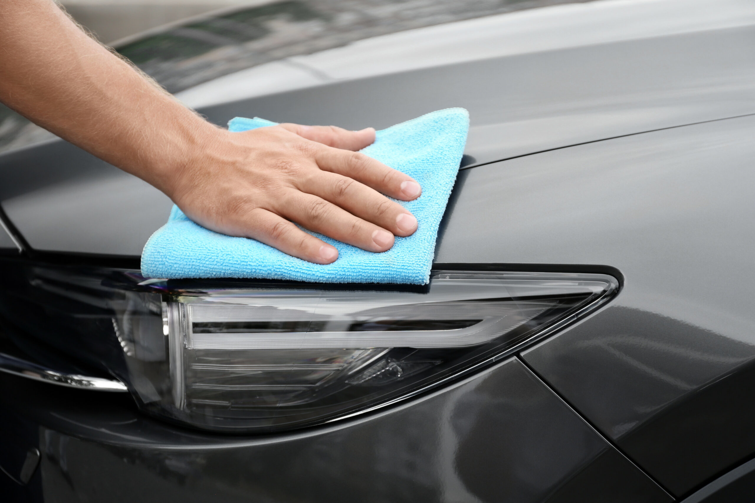 Man washing car headlight with rag, closeup
